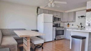 A modern kitchen with grey cabinets, a white refrigerator, a microwave, an oven, and a stainless steel trash bin. - Housepitality - Top Choice Flat - Great Location (Columbus)