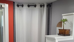 A bathroom with a white shelf, a potted plant, and a shower curtain.