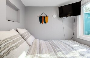 A bedroom with a bed, a mounted TV, and a wall-mounted decoration. - Modern cottage with full kitchen & private patio. Close to great hiking trails! (Oakland)