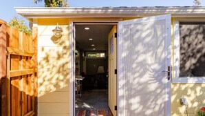 A house with a wooden fence, a white door, and a visible interior with a dining area.