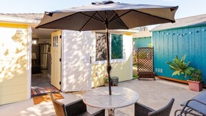 A patio with a round table and chairs, an umbrella, and a blue fence.
