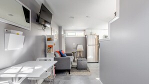 A modern kitchen with a dining area, grey walls, and a large window.