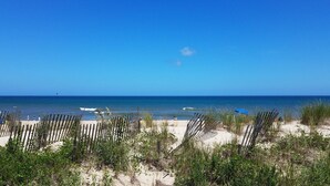 A beach with a wooden fence, sandy dunes, and a clear blue sky. - 2027 OPEN FOR BOOKING!  PIERVIEW 107 OCEAN-BEACHFRONT CONDO, 2BD&2BA SLEEPS 6 (Nags Head)