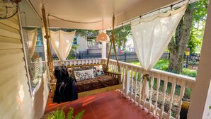 A cozy porch with a swing seat, a small table, and a bench.