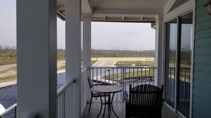 Een balkon met uitzicht op een weg en water, met een tafel en twee stoelen.