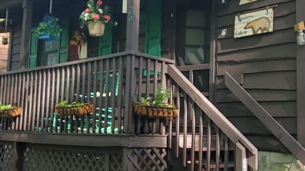 Une cabane dotée d’une terrasse en bois, d’un escalier et d’une pancarte indiquant qu’il s’agit d’une cabane.