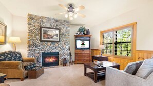 Una sala de estar acogedora con chimenea de piedra, un televisor y un mobiliario confortable.