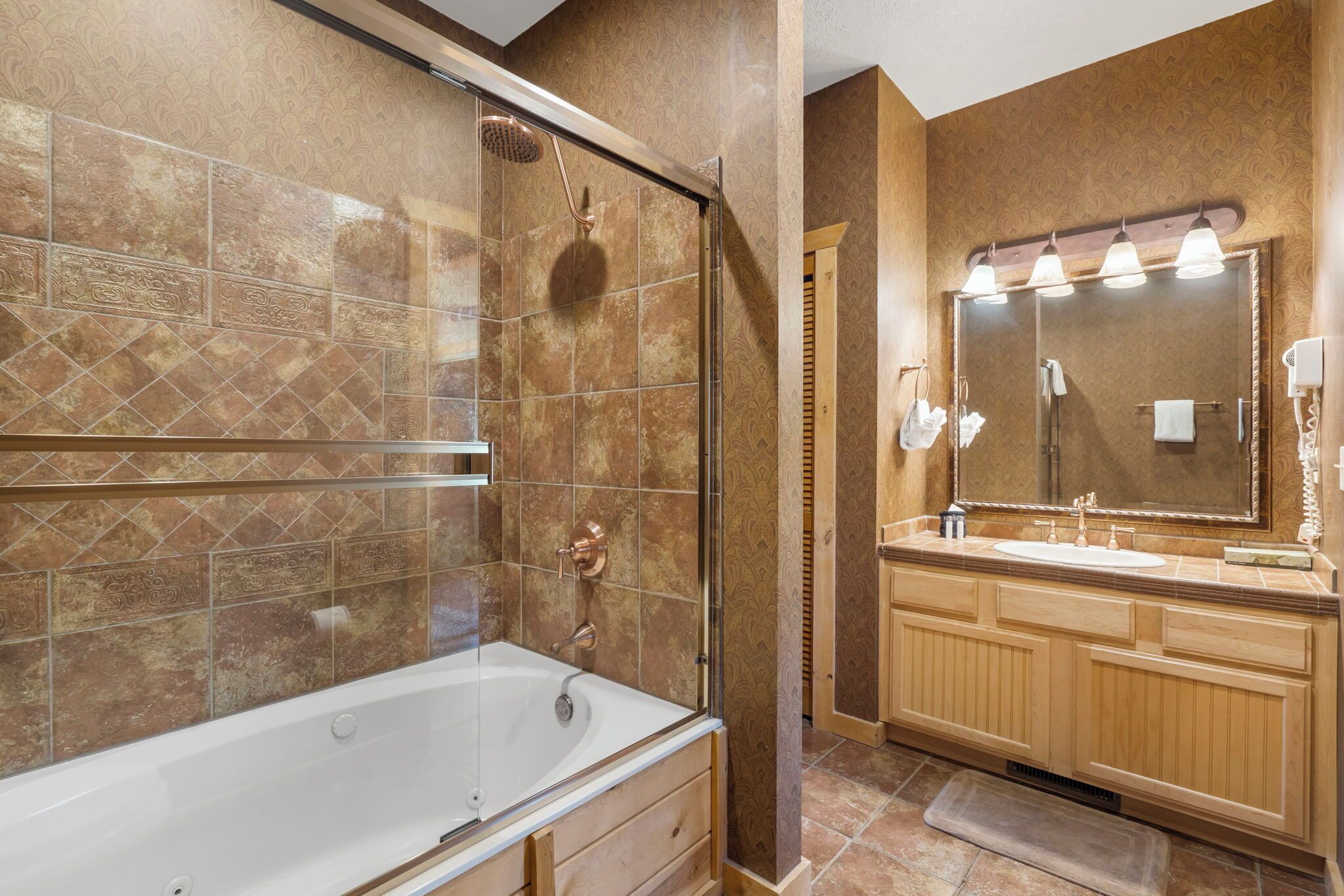 A modern bathroom with a glass-enclosed shower, a freestanding bathtub, and a vanity with a large mirror and multiple lights.