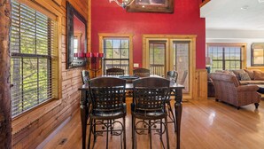 Un coin repas avec une table et des chaises en bois, des murs rouges et un lustre.