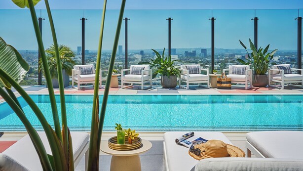 A rooftop infinity pool with white lounge chairs and potted plants, overlooking a cityscape. - The Sun Rose West Hollywood (West Hollywood)