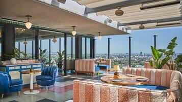 A modern lounge with a city view, featuring a mix of seating options, a bar area, and large windows.