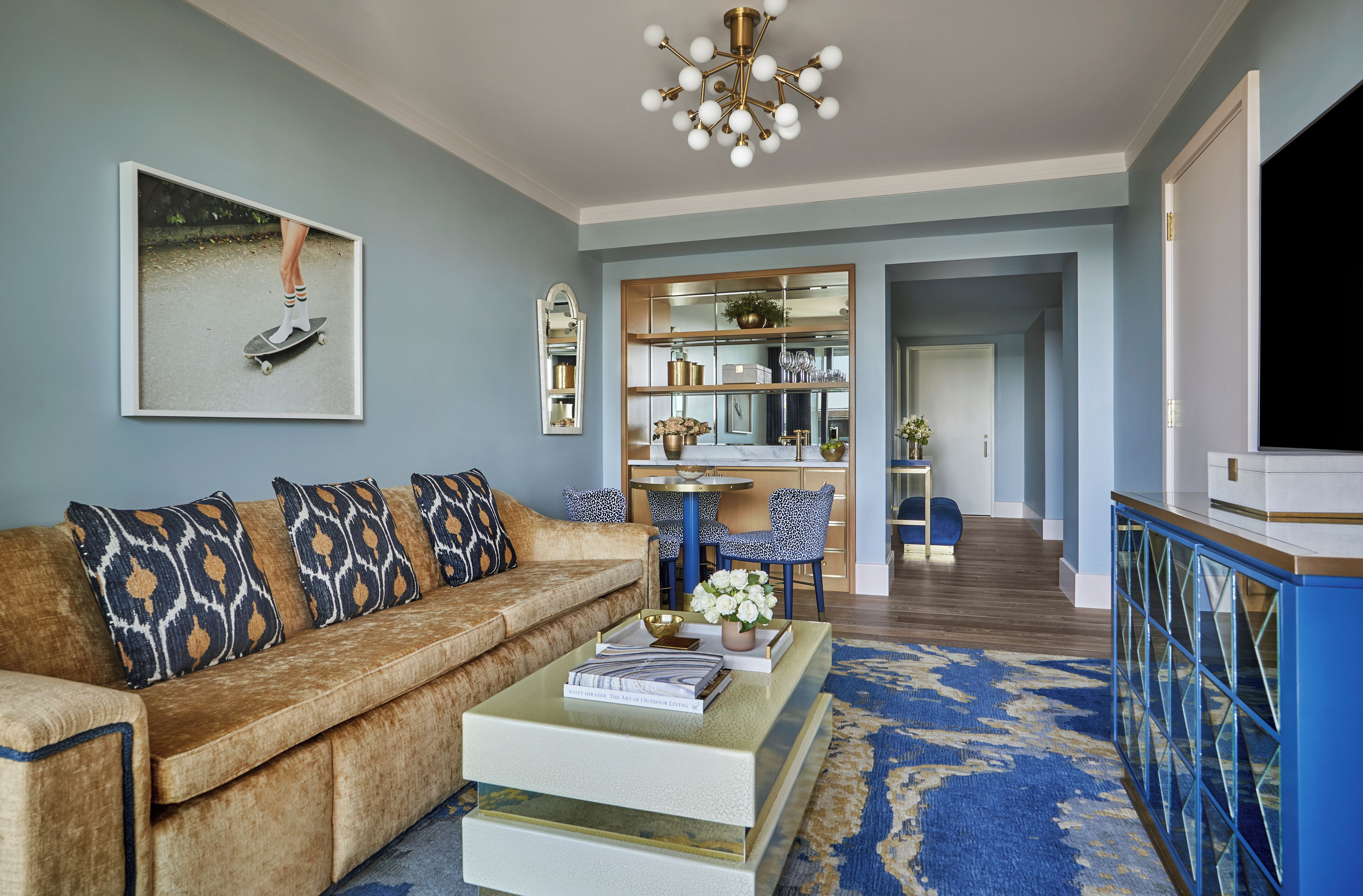 A living room with a brown sofa, a coffee table, and a blue patterned rug.