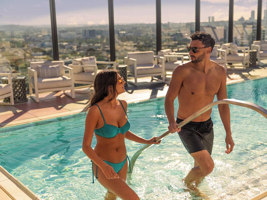 Una piscina al aire libre, sombrillas, sillones reclinables de piscina