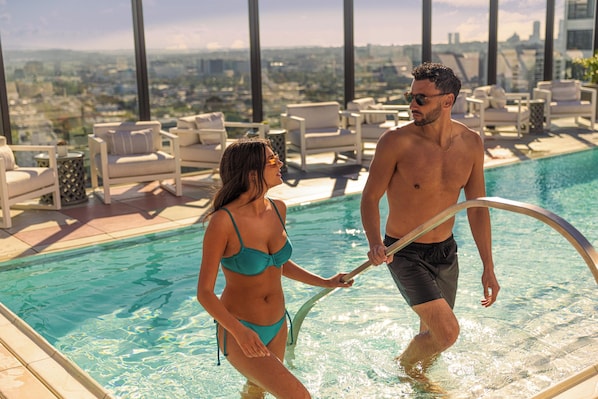 Una piscina al aire libre, sombrillas, sillones reclinables de piscina