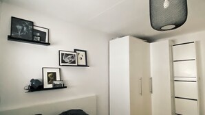 Een slaapkamer met een bed, een garderobe en een plank met ingelijste foto's.