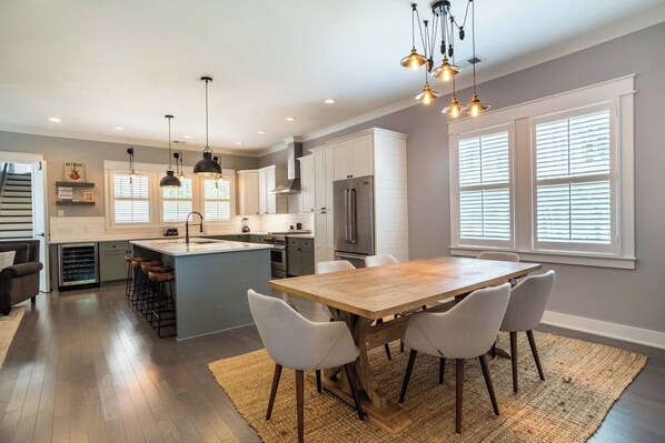 A modern kitchen with a central island, bar stools, and pendant lighting.