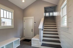 A staircase with a handrail, a door with a keypad lock, and a bench.