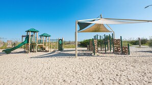 Un parque infantil en la playa con toboganes y estructuras para escalar.