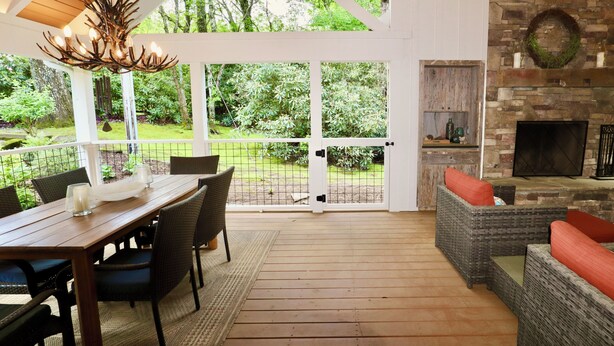 An outdoor patio with a wooden table and chairs, a wicker sofa, and a fireplace. - Idlewood Cottage: Cozy Home w/ Covered Porch, Firepit, Yard | 8 Min to Downtown (Highlands)