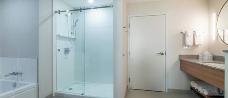 Ein modernes Badezimmer mit einer Duschkabine, einer Badewanne und einem Waschtisch mit Spiegel.
