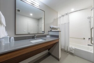 Un baño moderno con lavamanos, espejo y ducha.