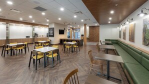Un restaurant moderne avec un plancher en bois, des chaises jaunes et marron, et un banc vert rembourré.