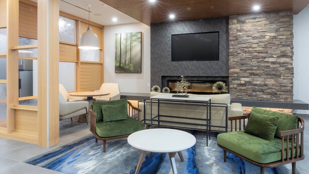 Un salon moderne avec un mur en pierre, une cheminée et un téléviseur à écran plat.