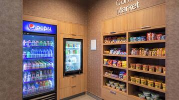 Une petite épicerie de quartier avec un réfrigérateur à boissons de la marque Pepsi et des étagères remplies d’en-cas et de boissons.