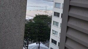 A view of a beach from a balcony with a building in the foreground.