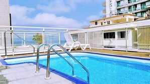 A pool area with lounge chairs and a railing on a deck.