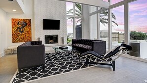Ein modernes Wohnzimmer mit Kamin, großen Fenstern und einem schwarz-weißen Teppich.