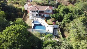 Una amplia casa con piscina, rodeada de abundante vegetación.