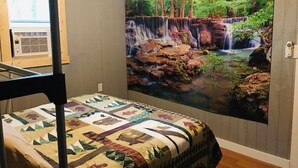 Ein Schlafzimmer mit Etagenbett, einer großen Wandmalerei eines Wasserfalls und einem Fenster mit Jalousien.