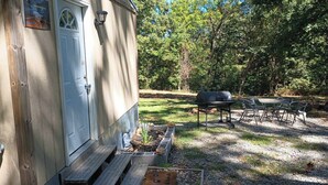 Eine Hütte mit Tür, Grill und Sitzgelegenheit im Freien.