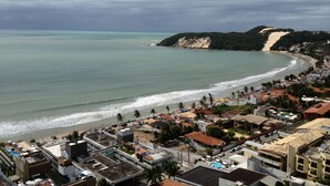 Une ville côtière avec une plage, des bâtiments et un paysage vallonné en arrière-plan.