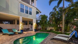 A swimming pool with lounge chairs, a covered patio, and a two-story building with balconies. - Lux Ocean View 4x4 for the Holidays! (Holmes Beach)