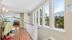 A spacious hallway with a dining area, large windows, and a view of greenery outside. - Lux Ocean View 4x4 for the Holidays! (Holmes Beach)