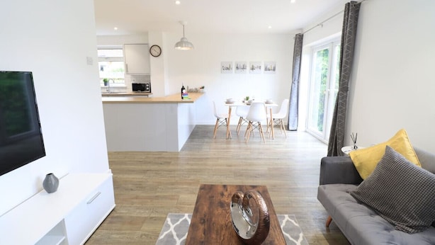Una sala de estar moderna con un sofá, una mesa de centro y un televisor sobre un mueble.