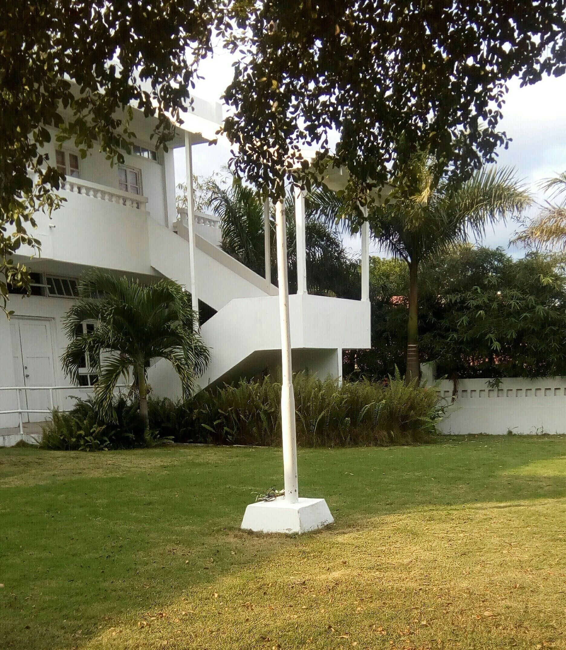A white sculpture in a grassy area with a white building in the background.
