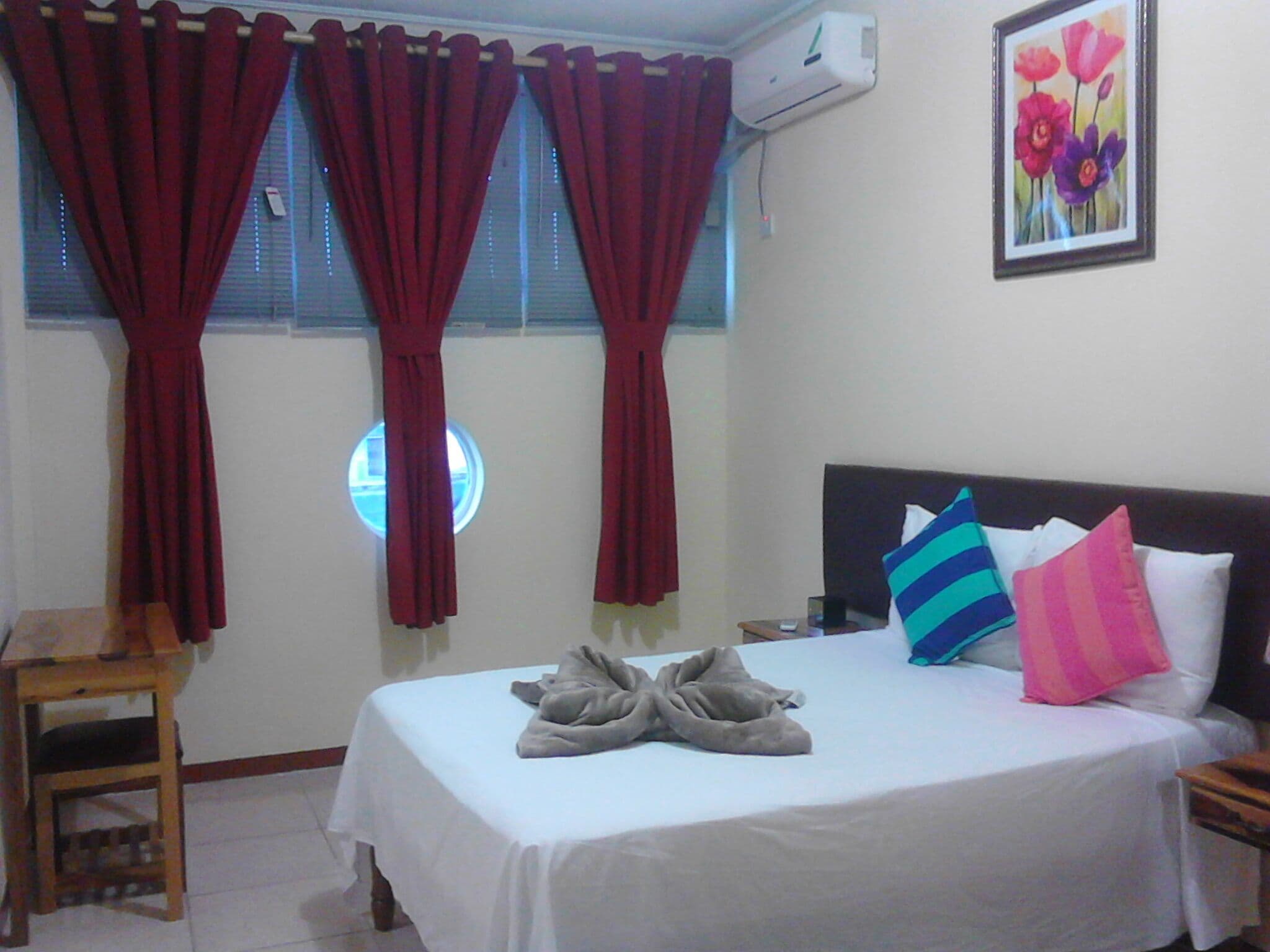 A hotel room with a bed, a chair, and a window with curtains.