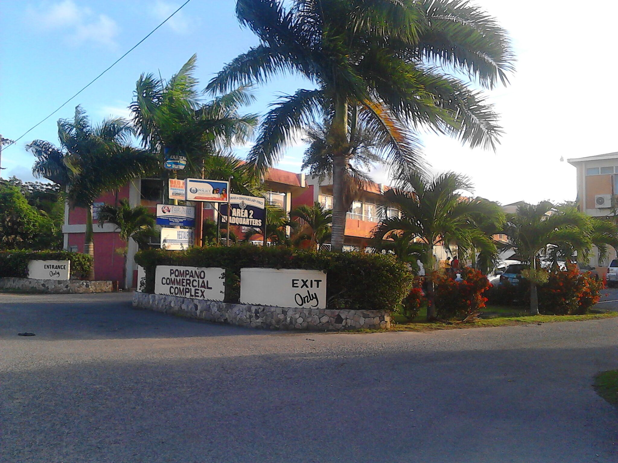 A commercial complex entrance with signage for 'Pompano Commercial Complex' and 'Exit Only' directions.