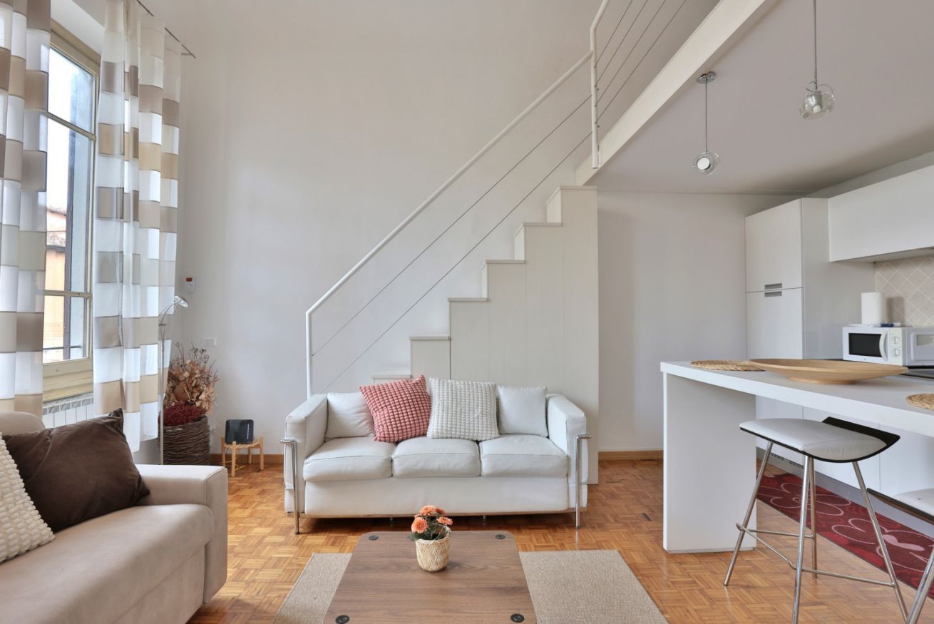 Un salon moderne avec un canapé, une table basse et un escalier menant à un espace cuisine.