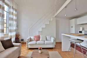 Una sala de estar moderna con un sofá, una mesa de centro y una escalera que lleva a una zona de cocina.