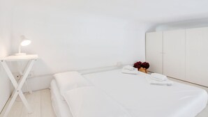 Ein schlicht eingerichtetes Hotelzimmer mit einem Einzelbett, einem Nachttisch mit Lampe und einem Kleiderschrank.