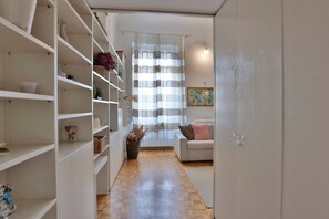 A hallway with white shelving units, a sofa, and a door. - GuestHost - Bright and functional 50sqm studio apartment that can accommodate up to 3 people. Located on the first floor, with elevator (not suitable for disabled), of a building overlooking Piazza San Marco and the homonymous Basilica, the apartment is  (Firenze)