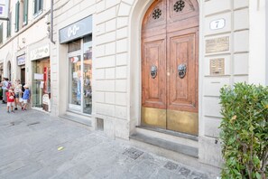 Une vue de rue avec un café, un cabinet d’avocats et une porte en bois traditionnelle.