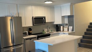 Une cuisine moderne dotée d’appareils électroménagers en acier inoxydable, de meubles blancs et d’un plan de travail en marbre.