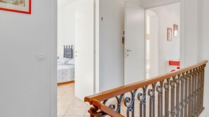 Ein Flur mit Holzwand und einer Tür zu einem Schlafzimmer, das ein Bett und einen Nachttisch zeigt.