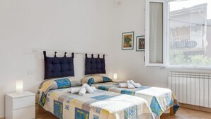 Ein Schlafzimmer mit zwei Betten, einem Nachttisch, einem Fenster mit Blick und einer Heizung.