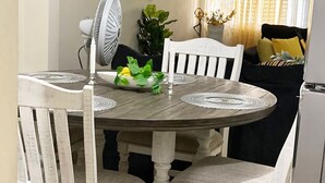 Una mesa de comedor con cuatro sillas, un ventilador y un cuenco decorativo con limones y hojas de menta.